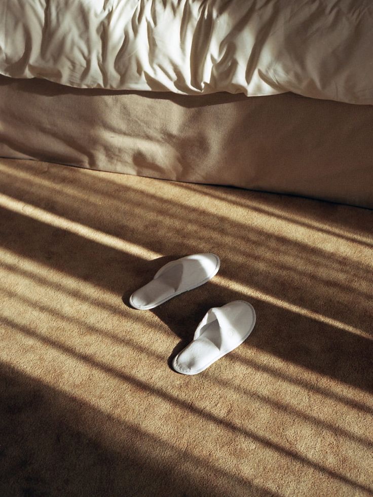 Pantofole ai piedi del letto, luce del mattino in un appartamento The Concept Studio
